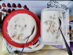 Cooked oat porridge with milk served in plastic containers