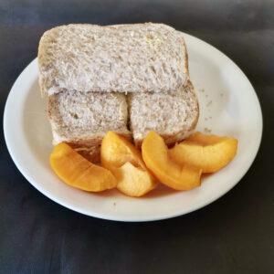 Plate with egg mayonnaise sandwich and sliced peach