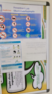 Clinic notice board with Prevention is Life poster, Sequence for putting on PPE poster and mother and child room poster.